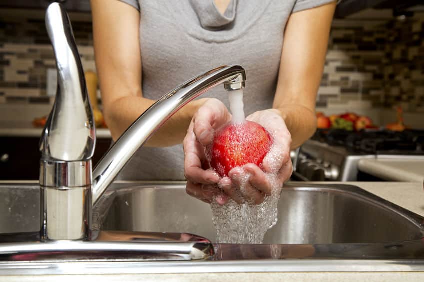 woman washing apples in the sink in the kitchen