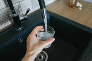 Woman filling cup with tap water that may have toxins in it